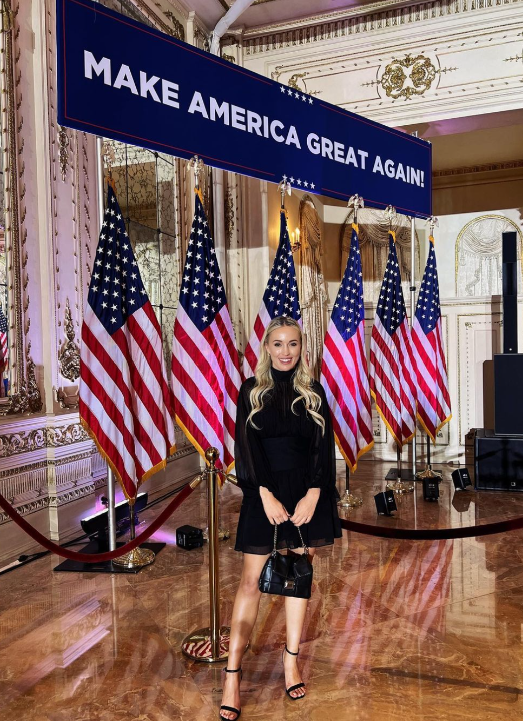 Ashton Munholland standing in front of American flags and Make America Great Again sign