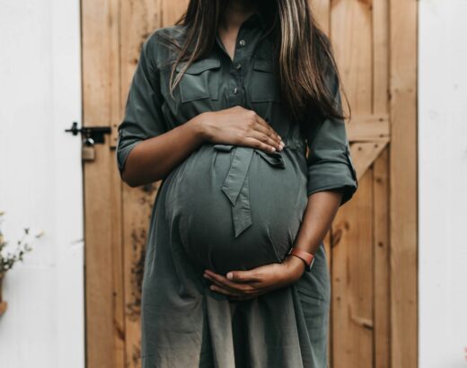 woman wearing green dress cradling her baby bump