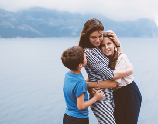 woman hugging her daughter and son against the background of a lake