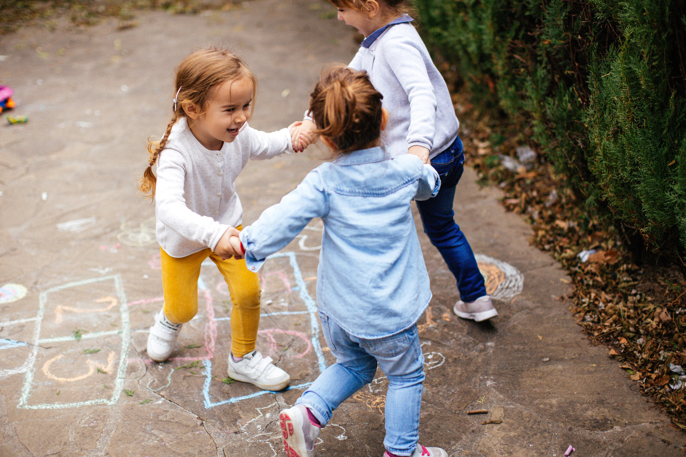 three girls playing ring around the rosy outside