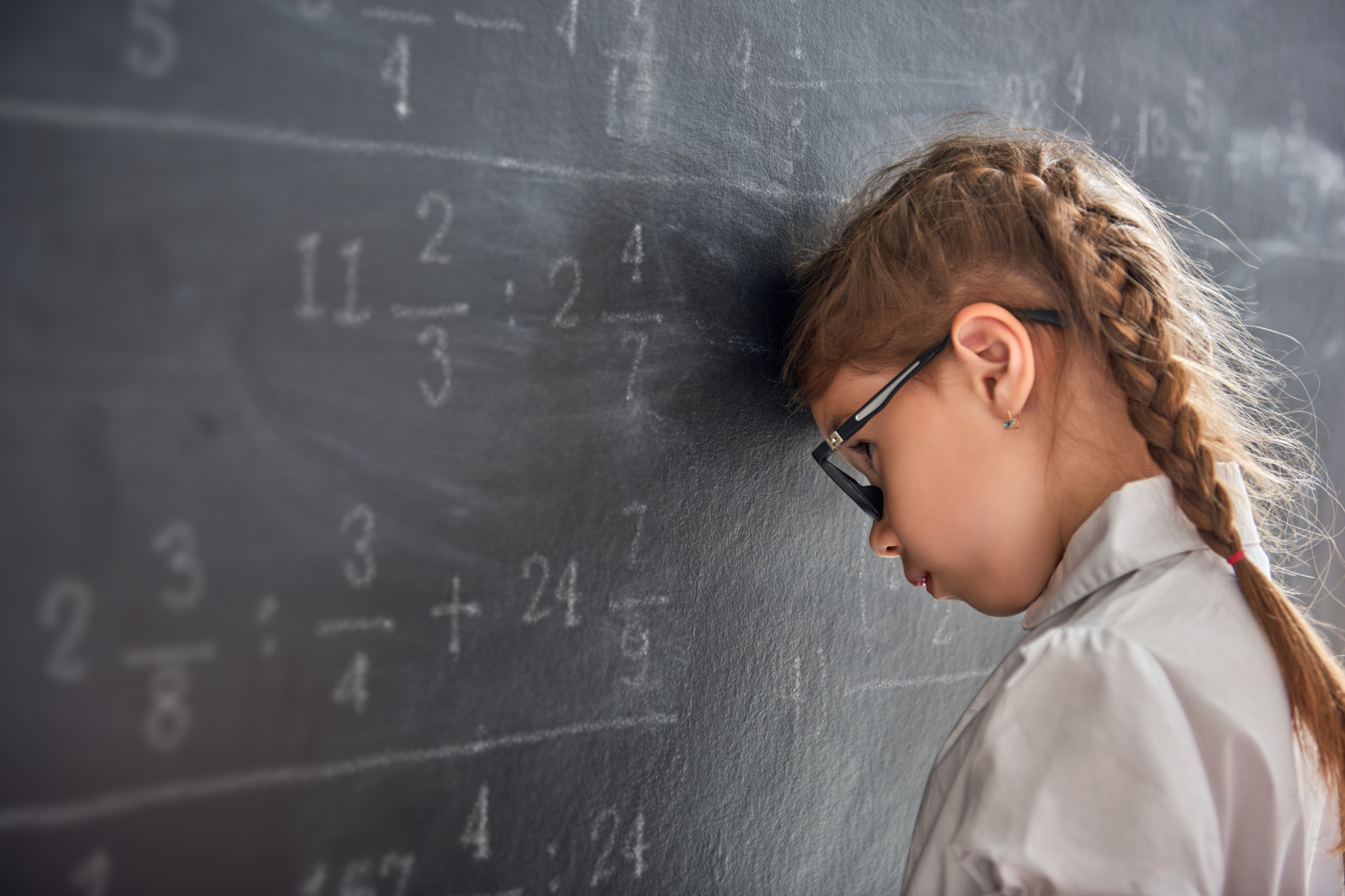 little girl frustrated with math at a blackboard