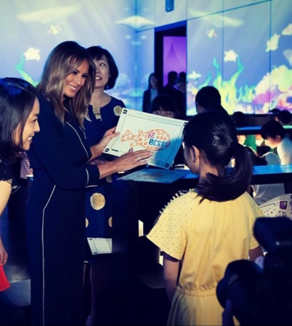Melania Trump with young girl looking at art that says Be Best